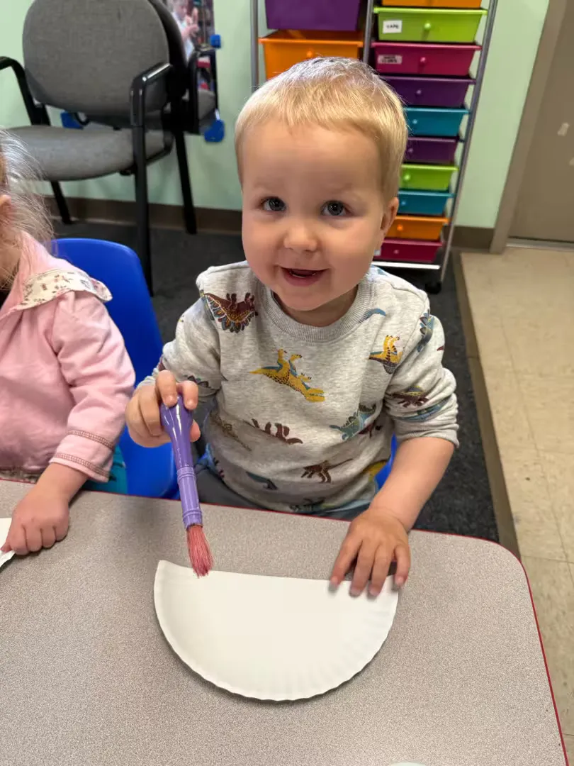 Child beginning to paint on a paper plate half.